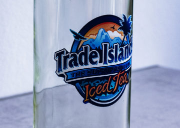 Bedruckte Glasflasche Eine Glasflasche, welche mit dem Logo von Trade Islands Iced Tea bedruckt ist