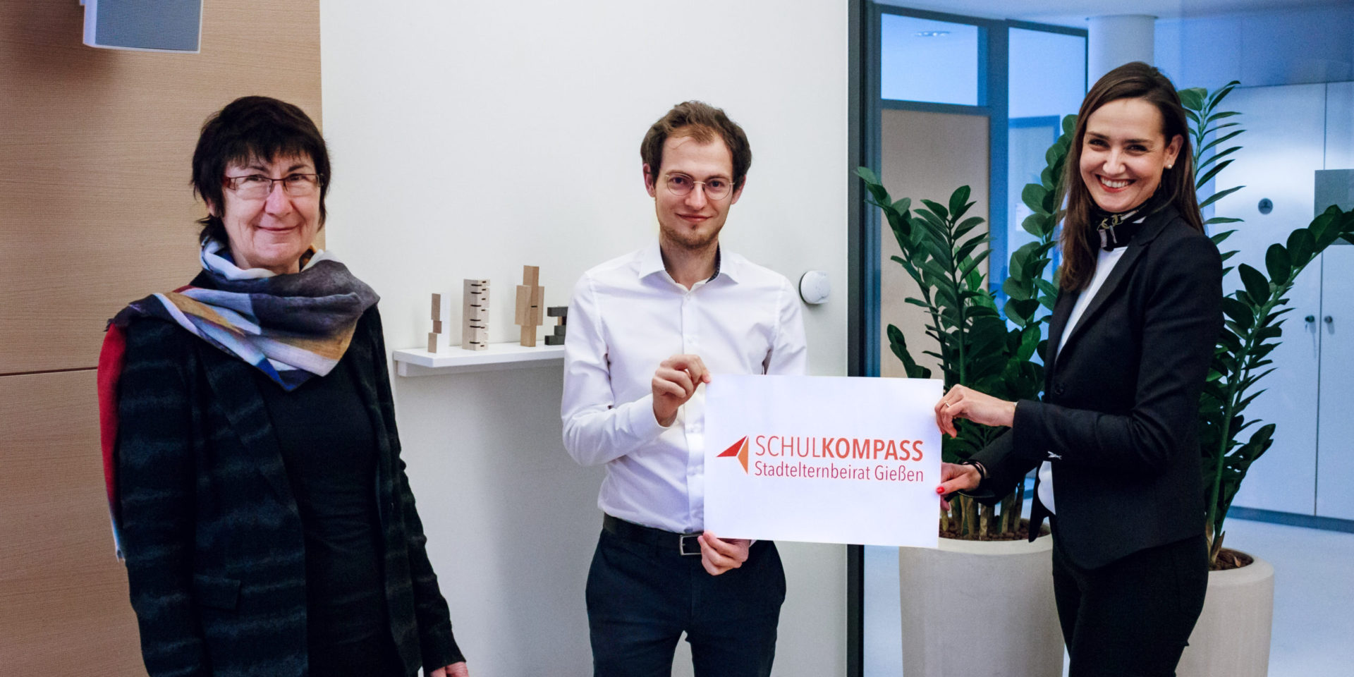 Gruppenbild mit v.l. Frau Eibelshäuser, Herr Barthel und Frau Zulauf die das Logo des Schulkompass in der Hand halten