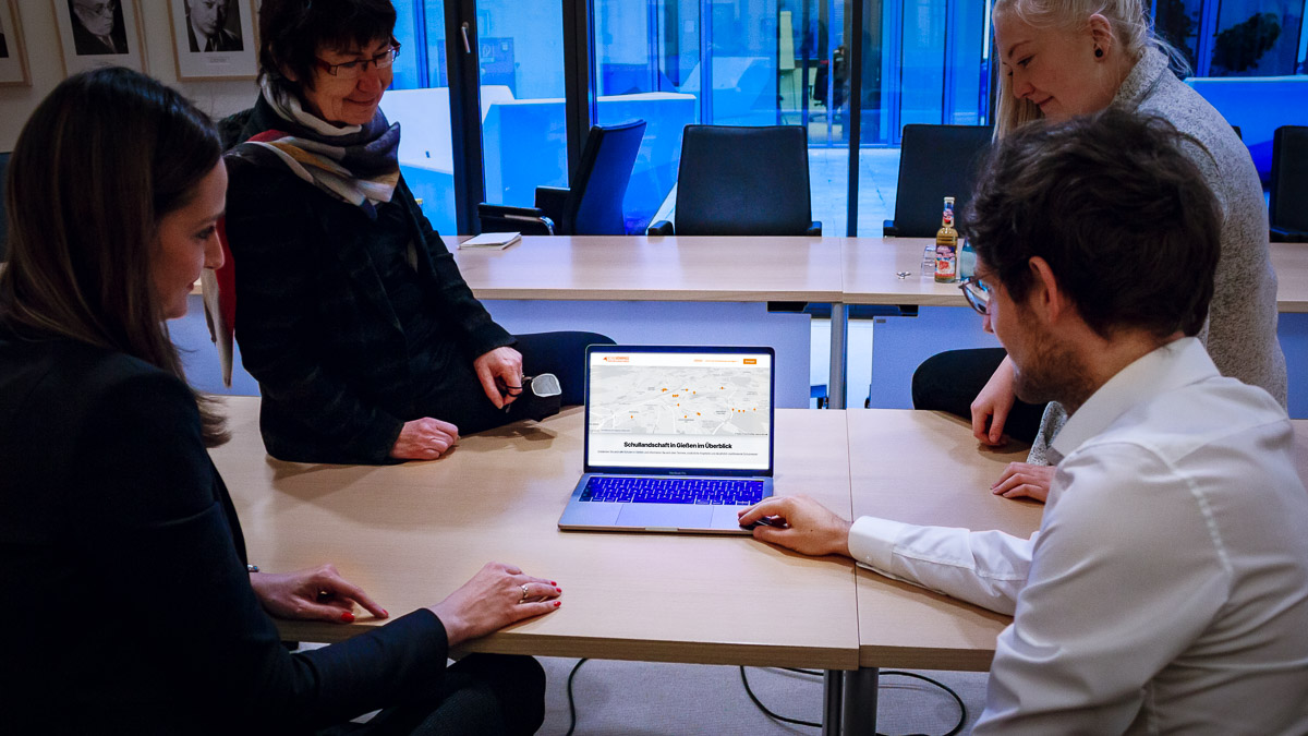 Frau EIbelshäuser, Zulauf + Ads&Friends Team sitzen um einen MacBook und betrachten die Schulkompass Webseite